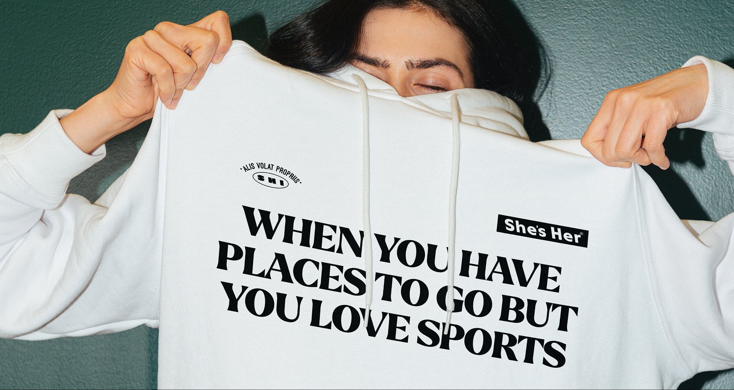 Person holding a white hoodie with text on it against a dark background